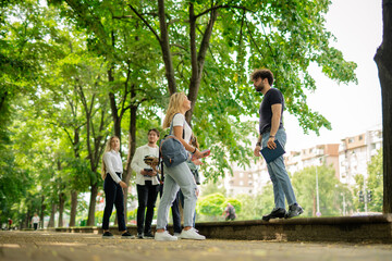 Fototapeta na wymiar Happy students having a conversation while standing on a sidewalk in front of the university