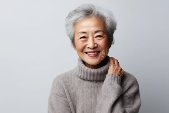 Medium shot portrait of a Chinese woman in her 90s in a white background wearing a cozy sweater