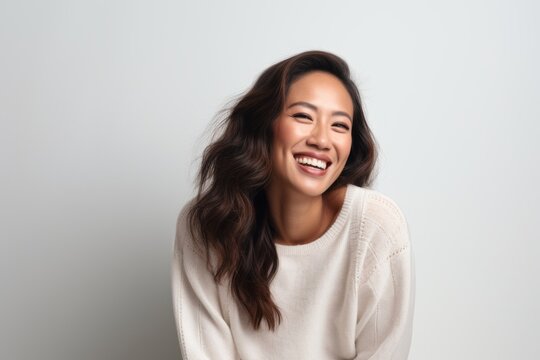 Lifestyle portrait of a Indonesian woman in her 30s in a white background wearing a cozy sweater