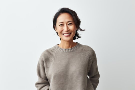Portrait of smiling mature asian woman in sweater standing against white background