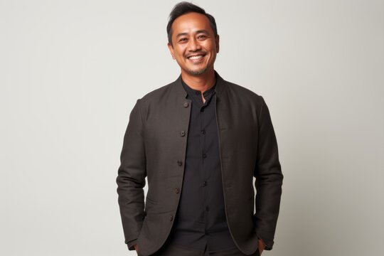 Portrait of a smiling asian man in a black suit on a white background
