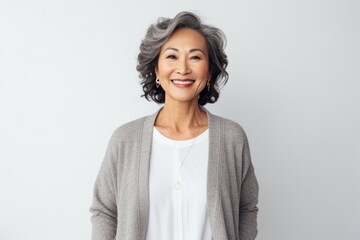 Lifestyle portrait of a Indonesian woman in her 50s in a white background wearing a chic cardigan