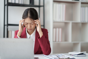 Asian businesswoman feeling stressed while doing paperwork in office