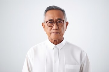 Obraz premium Medium shot portrait of a Indonesian man in his 60s in a white background wearing a chic cardigan