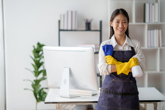 Asian young cleaning service woman worker clean table at home. Beautiful young girl housekeeper cleaner feel happy and wiping messy dirty counter for housekeeping housework or chores.