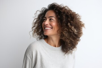 Lifestyle portrait of a Brazilian woman in her 40s in a white background wearing a cozy sweater