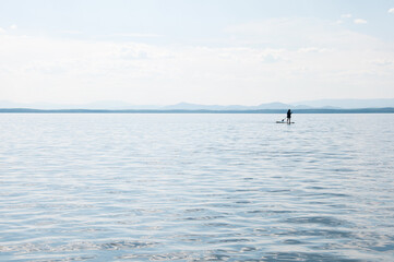 Obraz premium Seascape of Uvildy lake in summer with a silhouette of a supboarder, South Urals, Russia