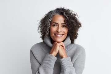 Fototapeta na wymiar Lifestyle portrait of a Brazilian woman in her 50s in a white background wearing a cozy sweater