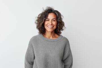 Lifestyle portrait of a Brazilian woman in her 50s in a white background wearing a cozy sweater