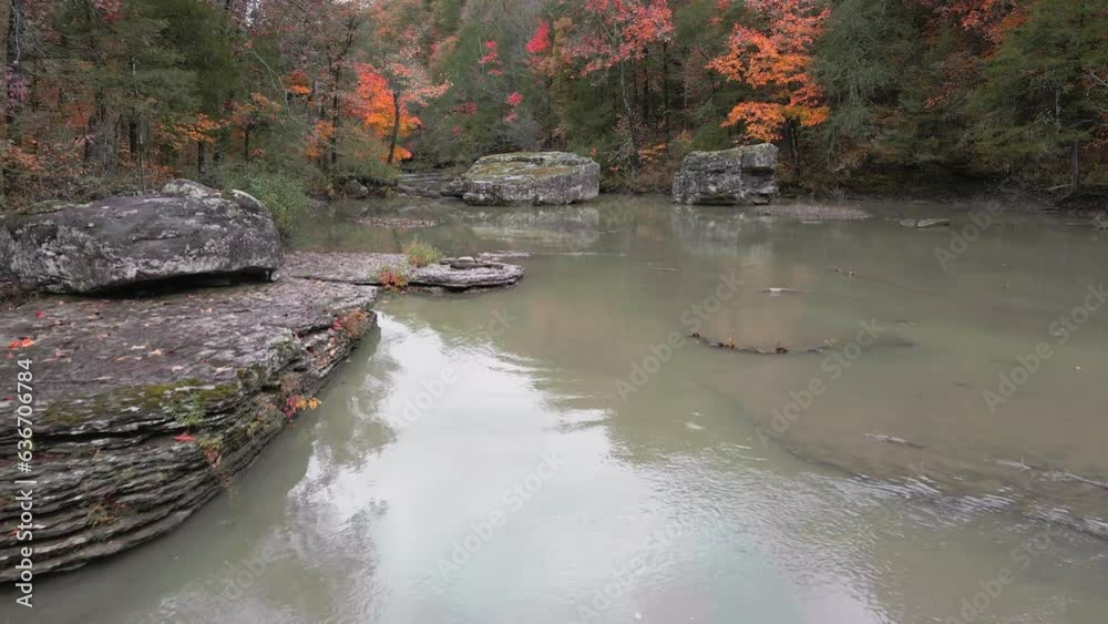Wall mural multiple waterfalls flow over rock cascade in the mountains during autumn with fall colored forest t