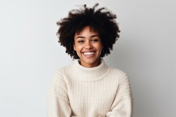 Obraz na płótnie Canvas Medium shot portrait of a Nigerian woman in her 20s in a white background wearing a cozy sweater