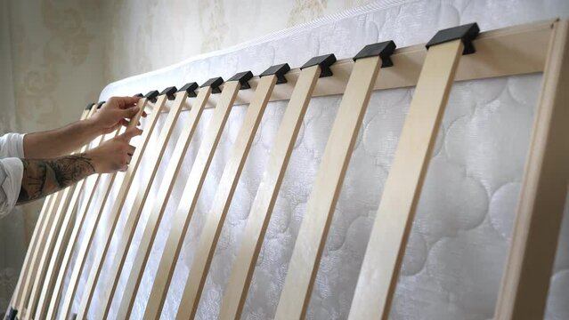 The process of assembling a baby bed with a mattress. Finishing a new bed frame with bed slats. Wood bed base. Bed frame of an orthopedic luxury. Interior structure of furniture.Self-assembly by guide