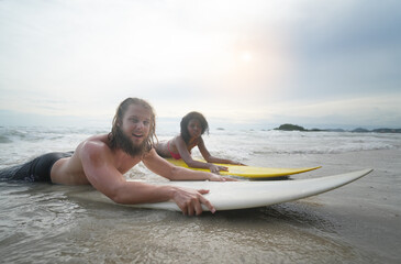 Happy couple surfing together on beach with surfing board in Pattaya, Thailand.