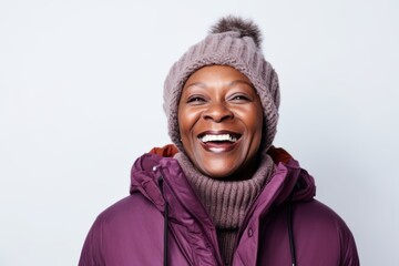 Medium shot portrait of a Nigerian woman in her 50s in a white background wearing a warm parka