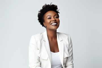 Lifestyle portrait of a Nigerian woman in her 50s in a white background wearing a classic blazer
