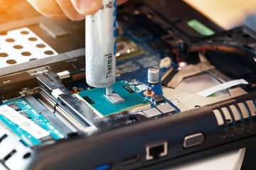 Hand a repairman uses thermal paste syringe apply thermal compound to a CPU. Master replaces thermal grease. Professional service and repair tech and electronics devices, laptops and PC