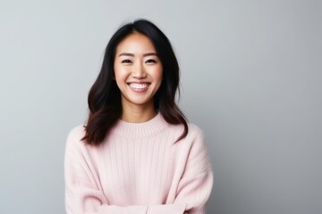 Fototapeta premium Portrait of a smiling young asian woman standing over gray background
