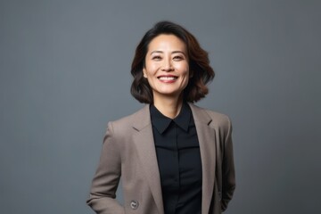 Portrait of a smiling asian business woman on grey background.