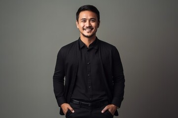 Obraz premium Portrait of a smiling asian man in black shirt on grey background