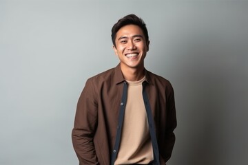 Fototapeta premium Portrait of a happy young asian man smiling on grey background