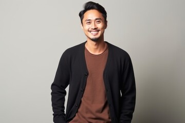 Fototapeta premium Portrait of a happy young asian man standing against gray background