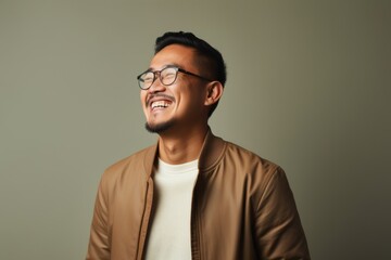 Obraz premium Handsome asian man in brown jacket and glasses on grey background