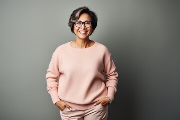 Obraz premium Portrait of a smiling mature woman in eyeglasses standing against grey background