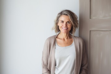 Obraz premium Portrait of smiling mature woman standing by door in room at home
