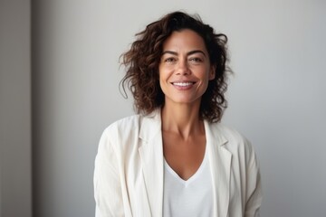 Medium shot portrait of a Brazilian woman in her 40s in a minimalist or empty room background wearing a chic cardigan