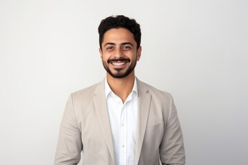 Portrait of a young Indian businessman smiling at camera isolated on a white background
