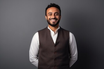 Obraz premium Portrait of a happy young indian man smiling against grey background