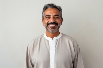 Obraz premium Portrait of Indian man smiling and looking at camera against grey background