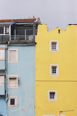 Fototapeta na wymiar Small windows of a blue and yellow residential building in Europe - the concept of minimalism