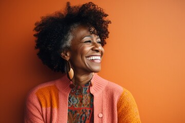 Obraz na płótnie Canvas Portrait of a beautiful young african american woman laughing against orange background