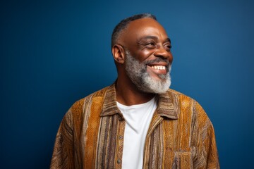 Fototapeta premium Portrait of a happy mature african american man laughing against blue background