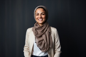Portrait of a smiling muslim woman wearing hijab over grey background