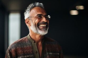 Lifestyle portrait of a Saudi Arabian man in his 50s in an abstract background wearing a chic cardigan
