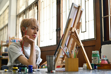 The portrait image of an attractive Young Asian LGBT teenage boy with colored hair focuses on a colored painting art piece, LGBT lifestyle, and Artwork concepts.