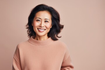 Fototapeta premium Portrait of a smiling asian woman looking at camera isolated over beige background