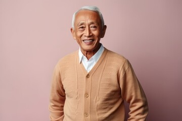 Obraz premium Portrait of a smiling senior asian man standing against pink background