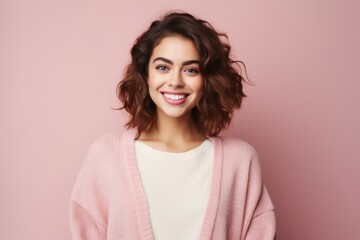 Fototapeta premium Portrait of a beautiful young woman smiling at camera isolated over pink background