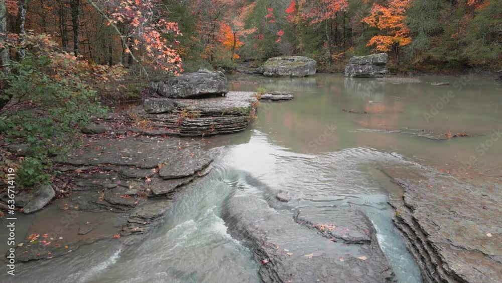 Wall mural multiple waterfalls flow over rock cascade in the mountains during autumn with fall colored forest t