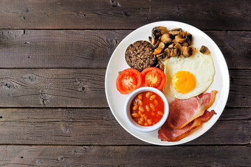 Full Scottish breakfast with haggis. Top view over a rustic dark wood background.