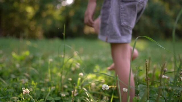 little girl walks on the grass barefoot in the park. happy family kid dream concept. bare feet close-up walks lifestyle on the grass in summer child. daughter walks barefoot on the grass in the park