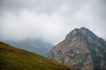 Beautiful mountain landscape with rocks, fog and paragliders - 636721139