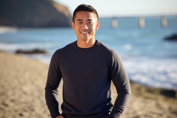 Medium shot portrait of a Chinese man in his 30s in a beach background wearing a cozy sweater