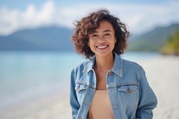 Medium shot portrait of a Indonesian woman in her 30s in a beach background wearing a denim jacket