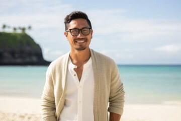 Lifestyle portrait of a Indonesian man in his 30s in a beach background wearing a chic cardigan