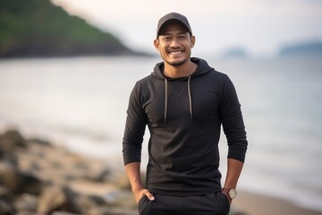 Medium shot portrait of a Indonesian man in his 30s in a beach background wearing a pair of leggings or tights