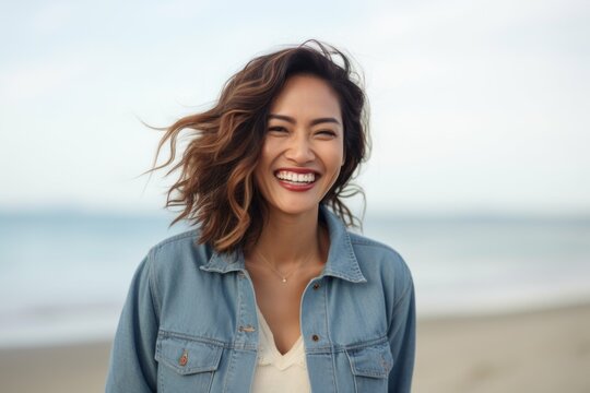Medium shot portrait of a Indonesian woman in her 30s in a beach background wearing a denim jacket